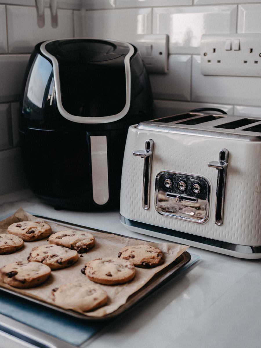 Air fryer and toaster on a kitchen counter beside a tray of cookies