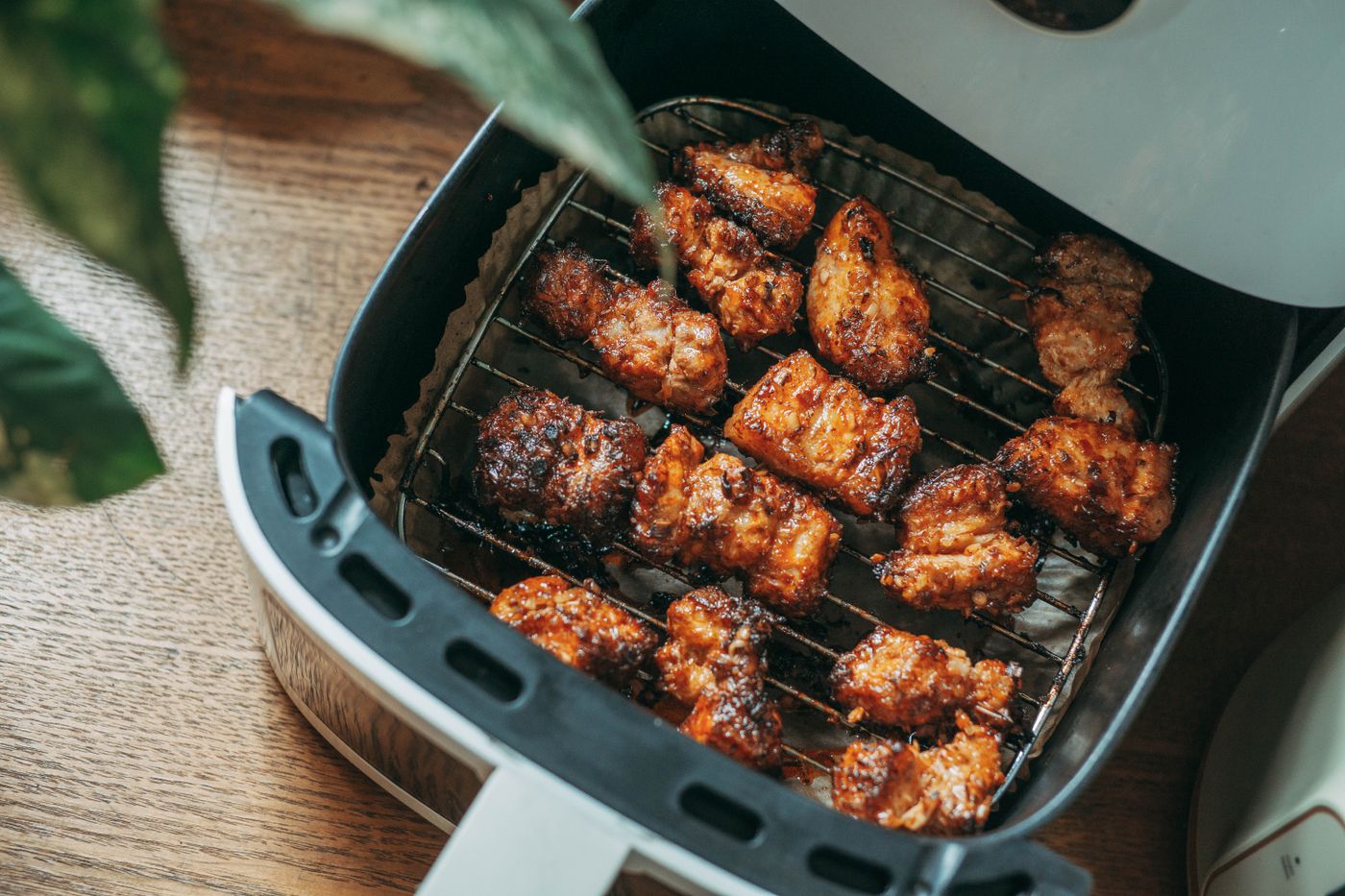 Chicken pieces on a rack in an open air-fryer drawer