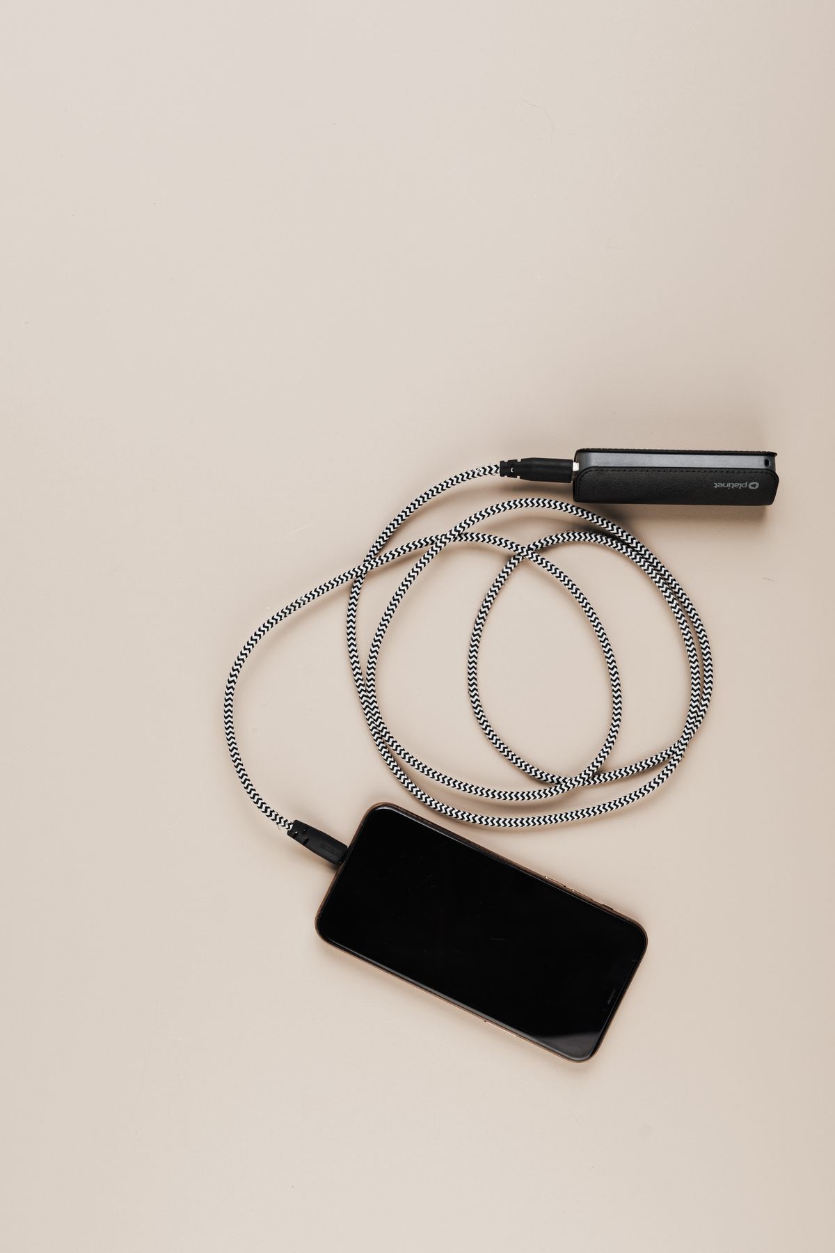 A phone connected by a cable to a power bank on a beige surface